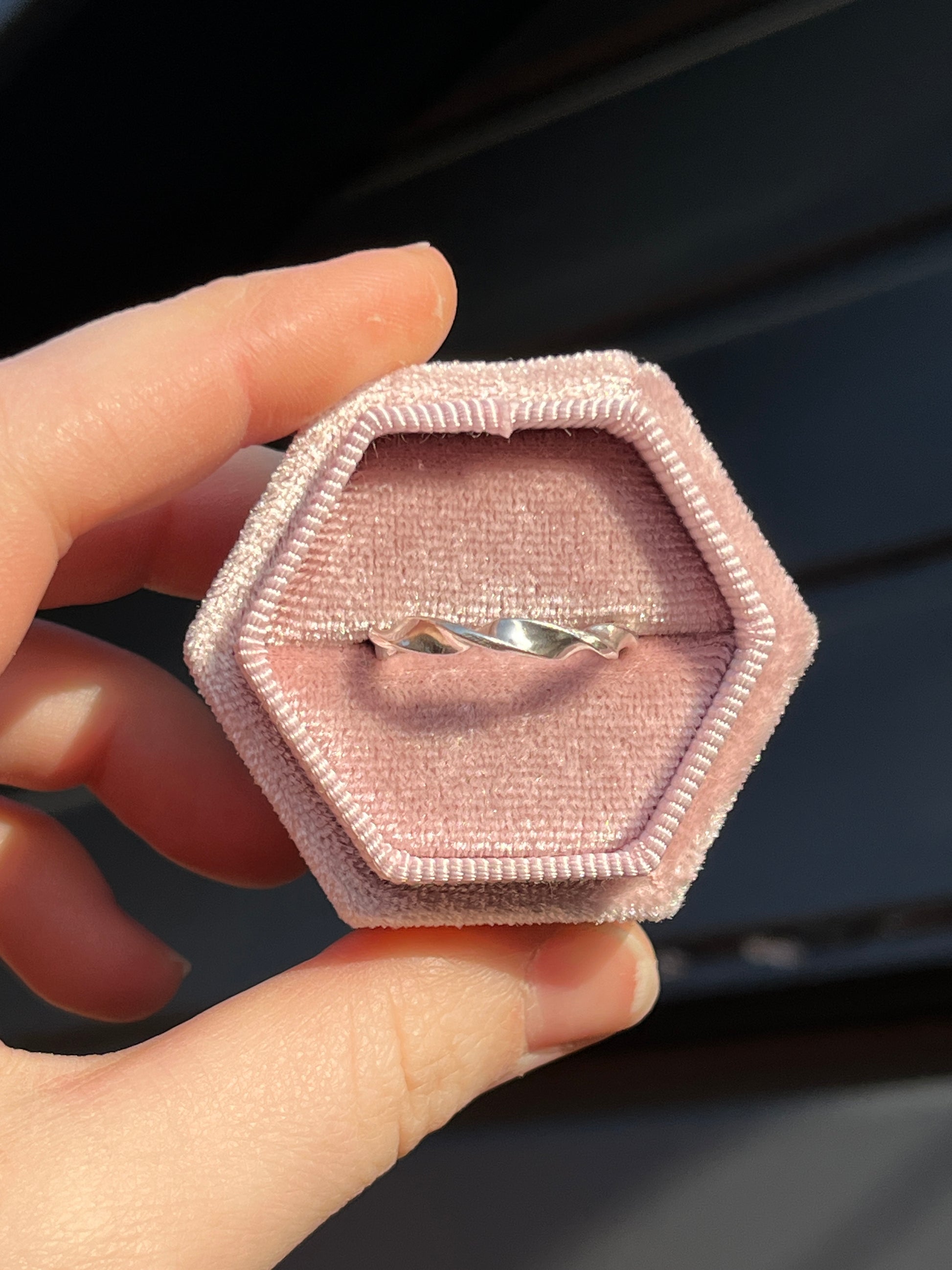 The Helix Ring, lit by the sun and pictured agains black wood backdrop