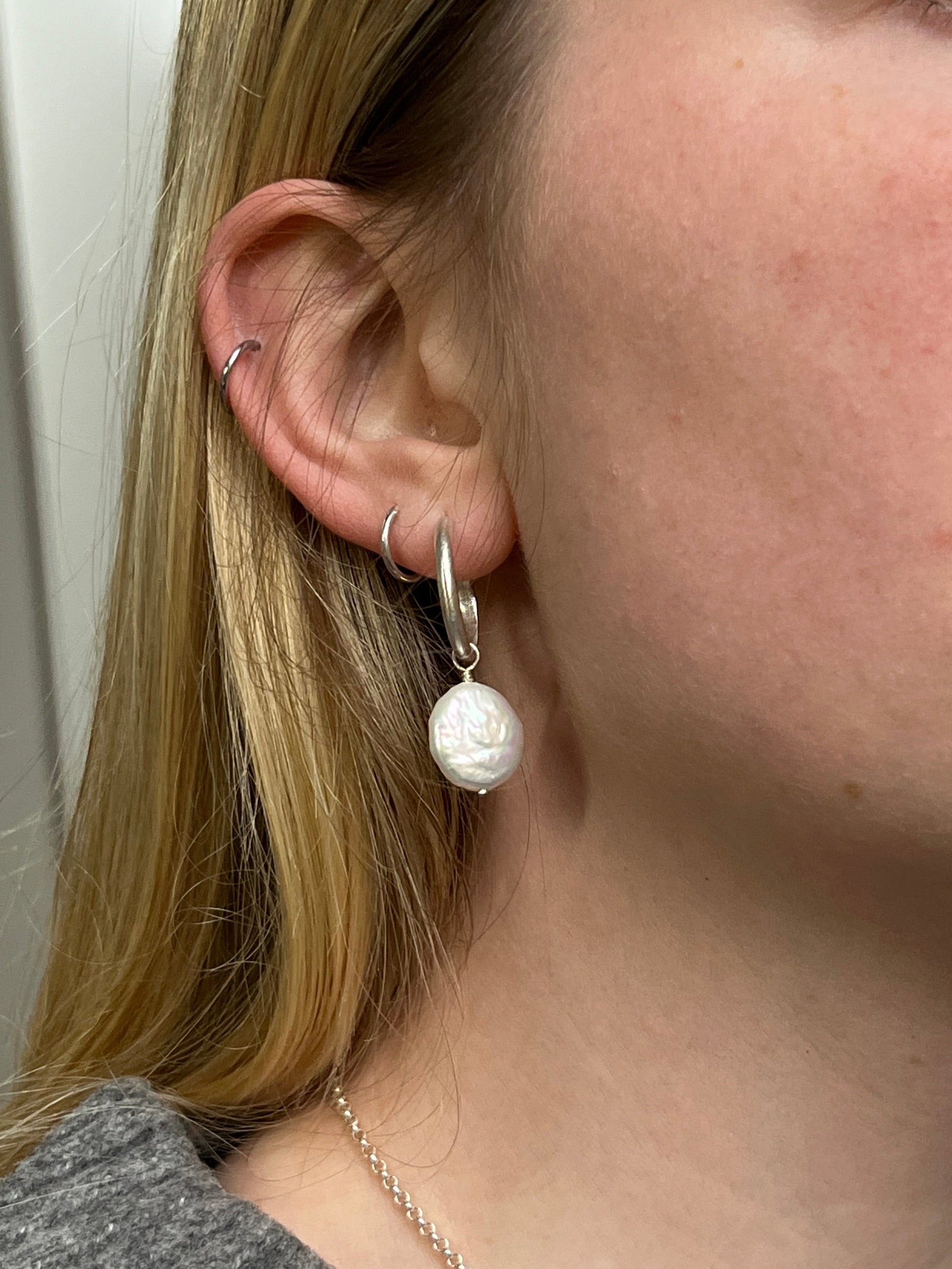 Supermoon hoop modelled in ear. Silver 3/4 hoop with a flat, round coin pearl drop hanging from the hoop.