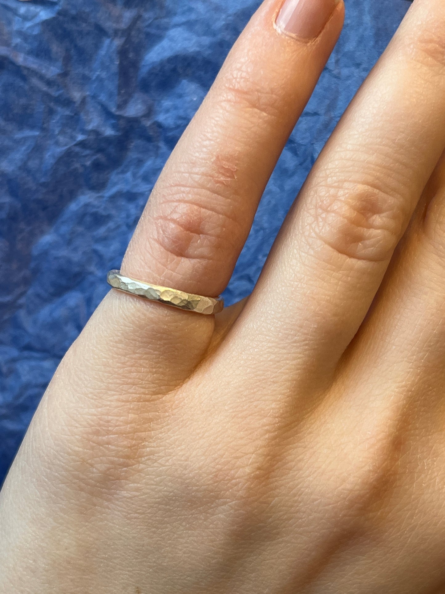 the satin finished hammered ring can be seen on a pinky finger