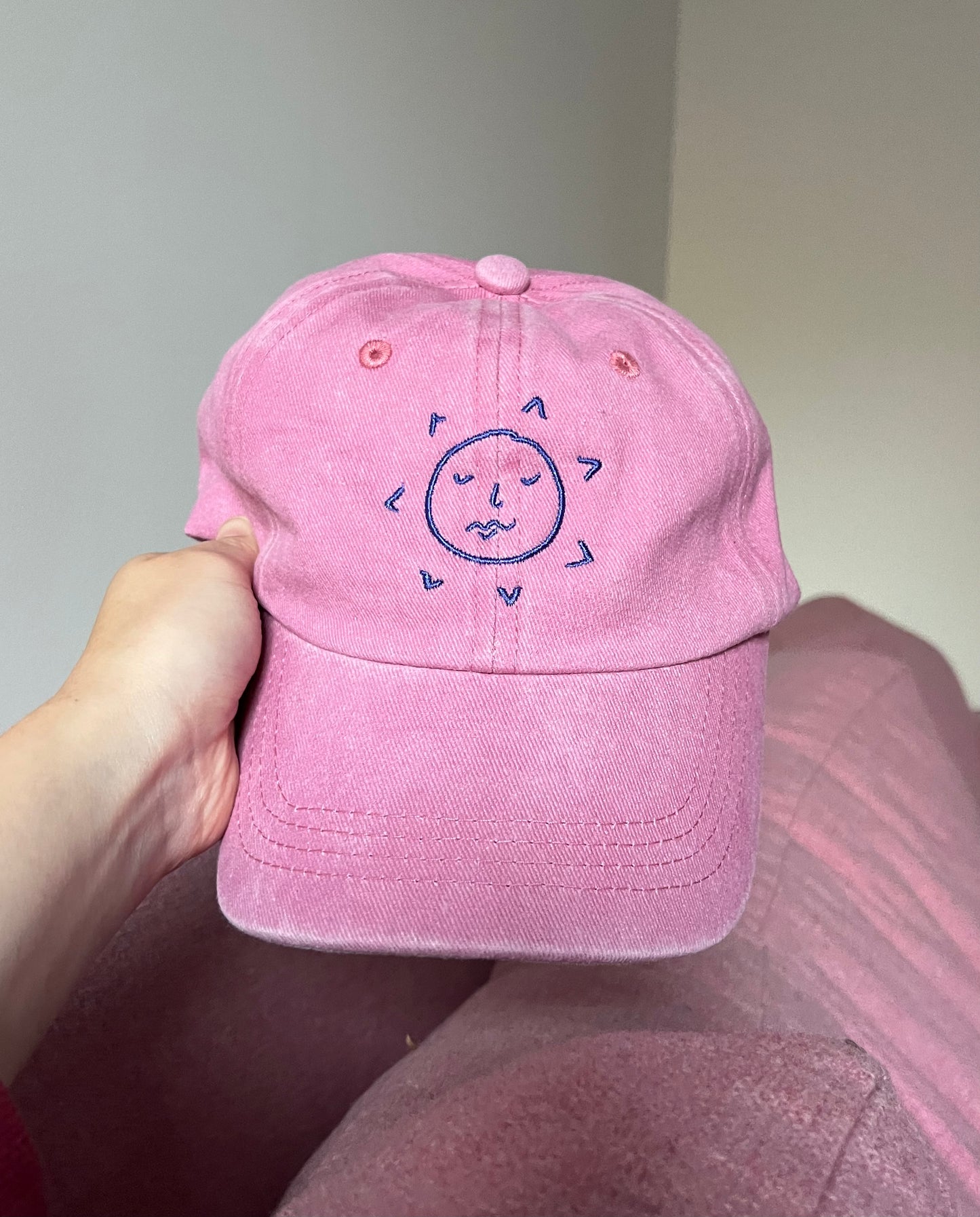 the sunslices pink cap pictured from the front showing the sunface logo