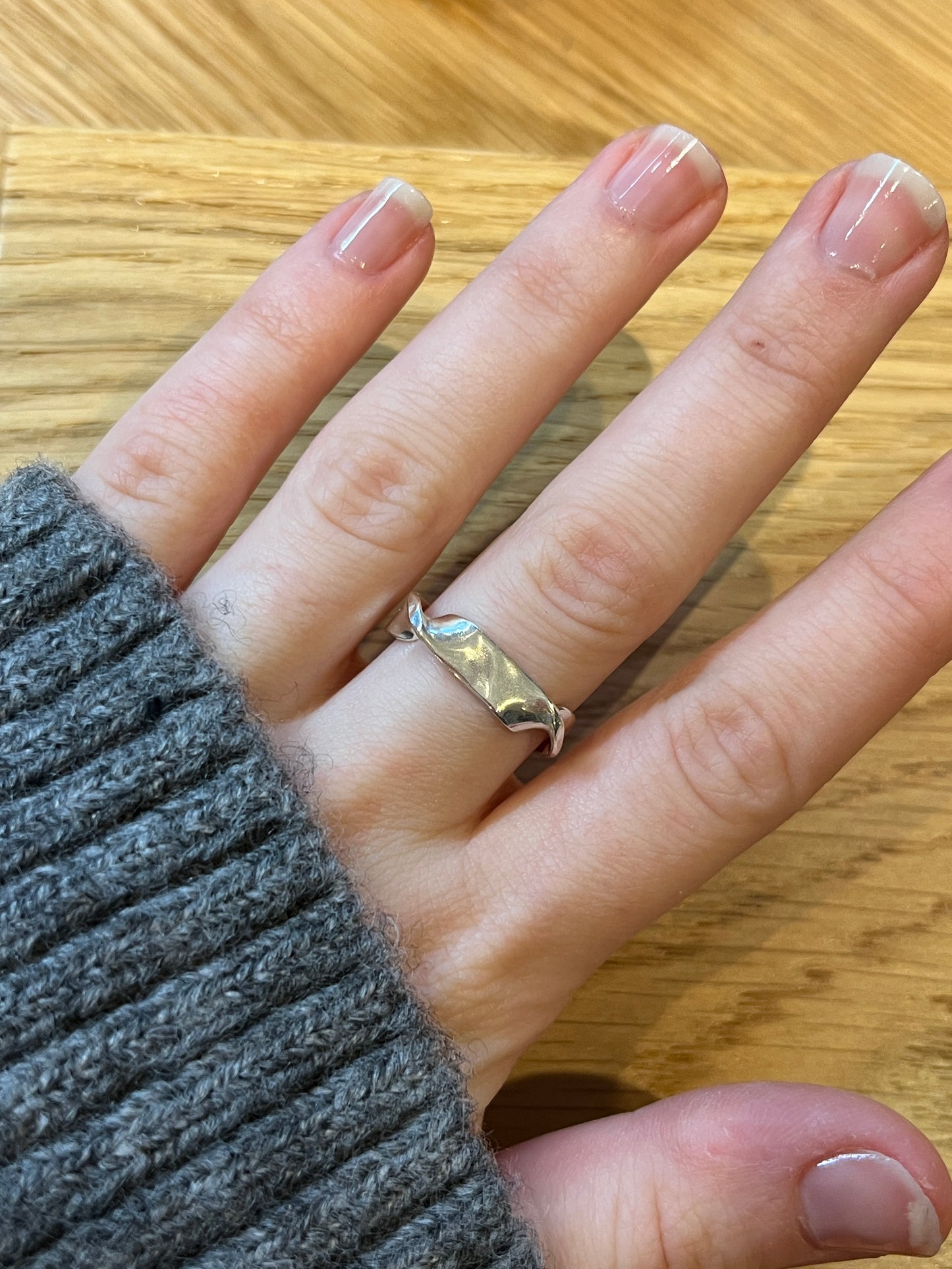 twirl ring 1 pictured on hand against grey knitted jumper