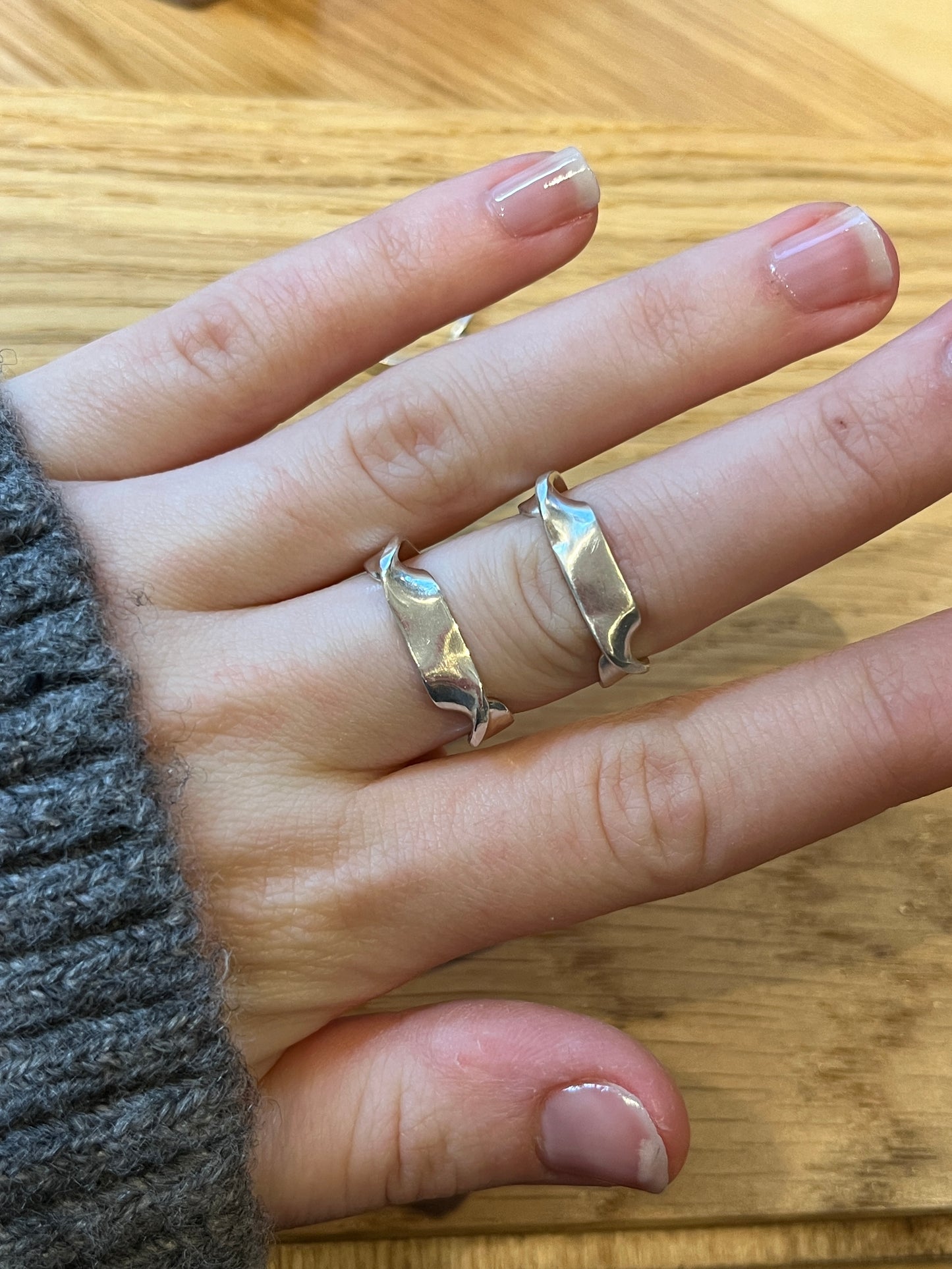 a comparative photo of the twirl ring vs the mirror ring, highlighting the different directions of turns in the metal