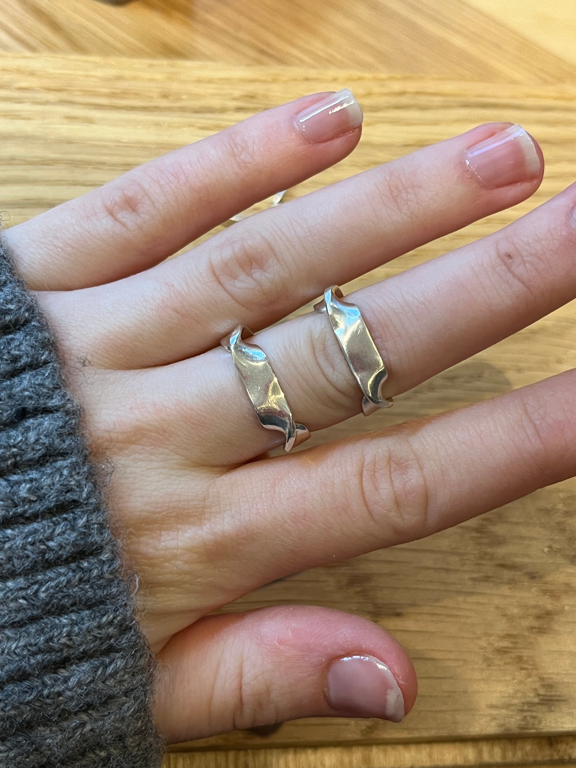 a comparative photo of the twirl ring vs the mirror ring, highlighting the different directions of turns in the metal