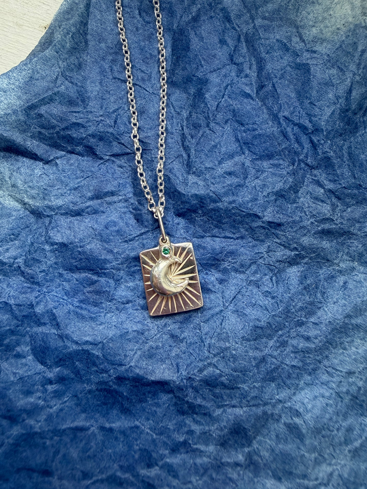 Necklace with a moon pendant on a blue textured background