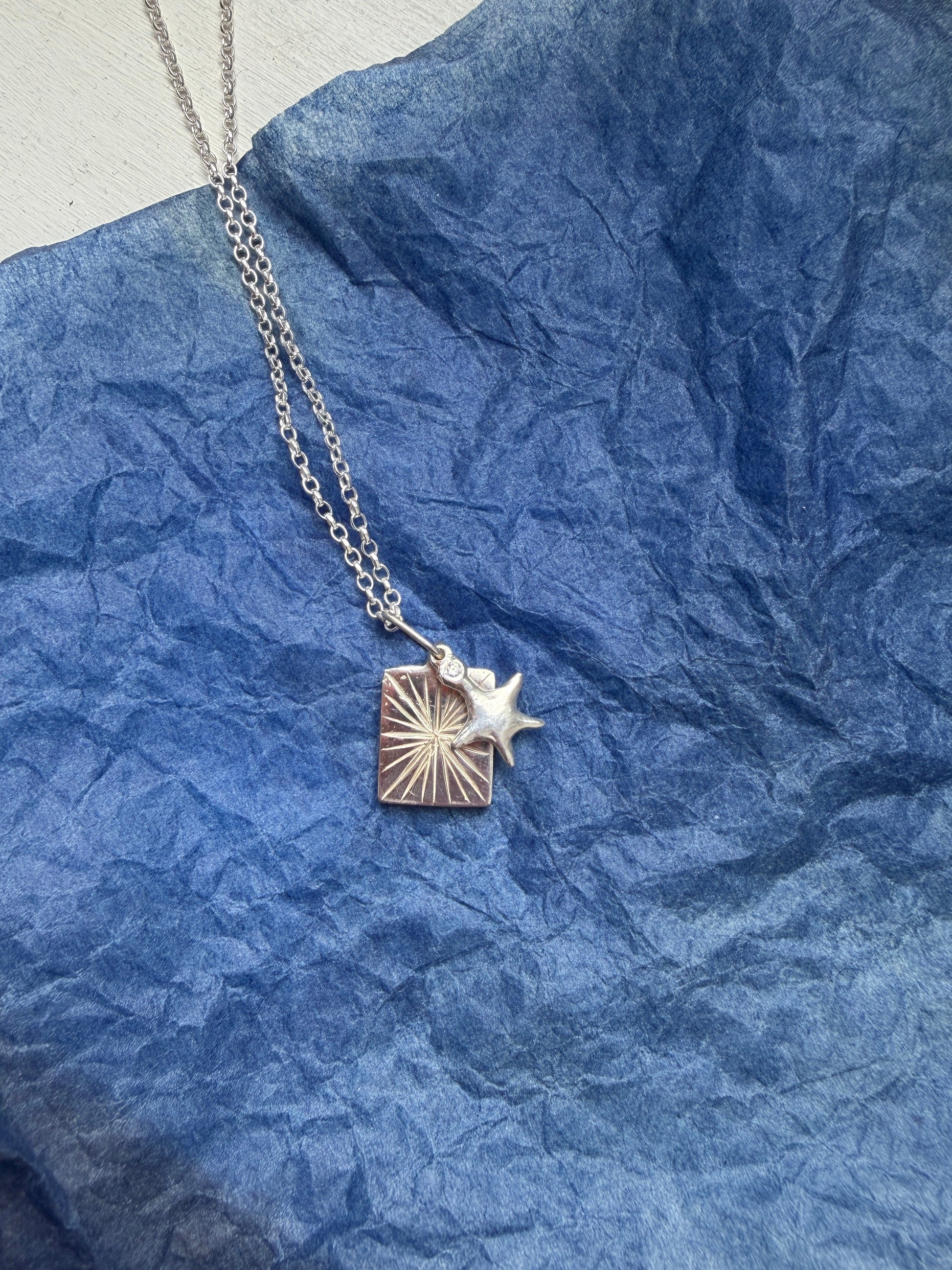 Silver necklace with a star pendant on a blue textured background