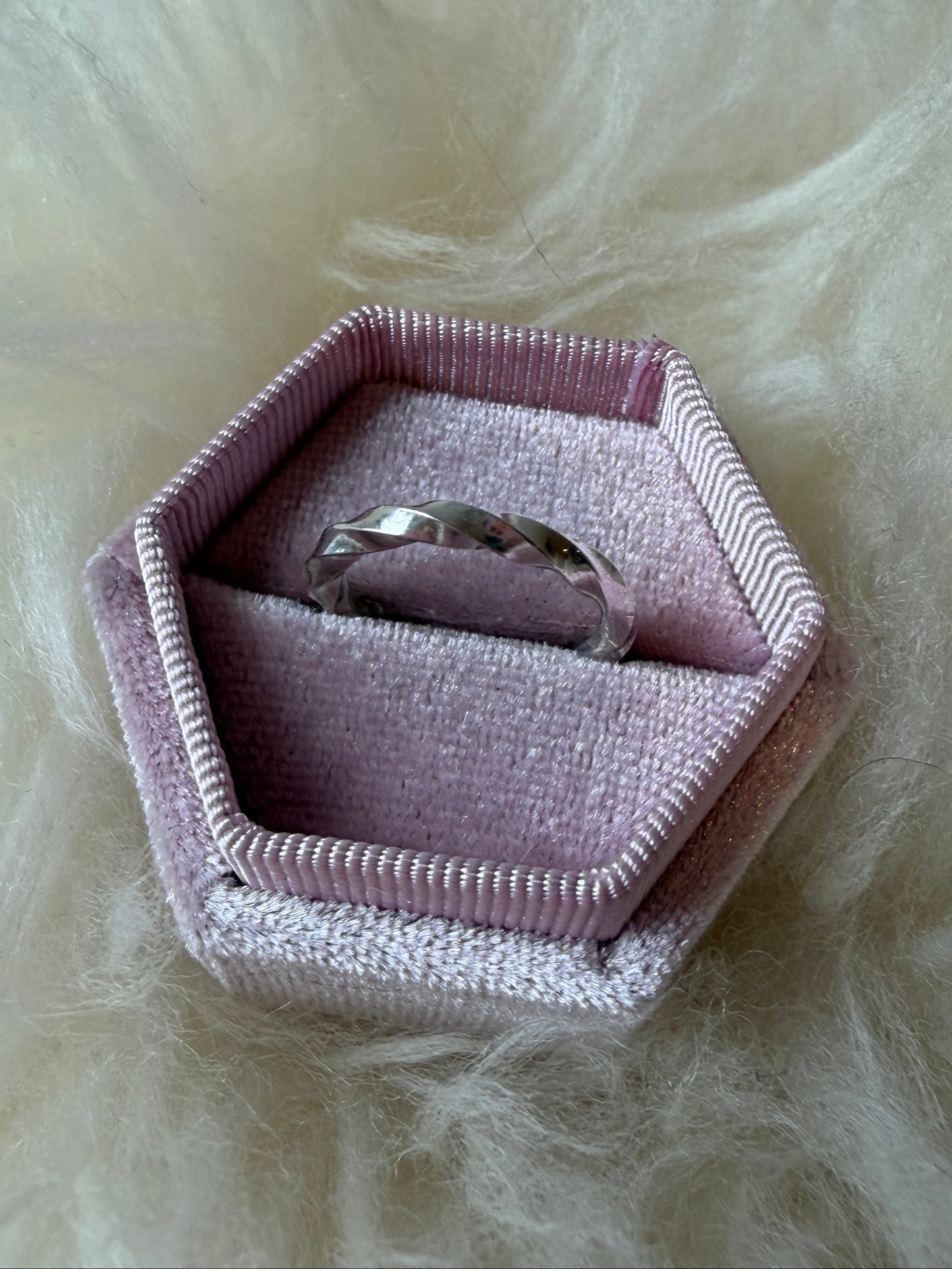 Sterling silver ring with continuous twists in a pink ring box against a white fur background.