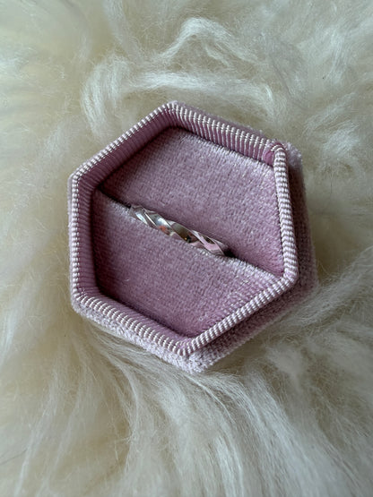 Sterling silver ring with continuous twists, pictured front on, in a pink ring box against a white fur background.