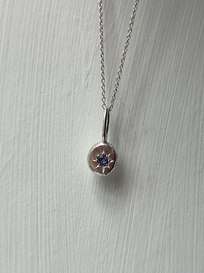a sterling silver pendant with a star set tanzanite gemstone on a silver trace chain, pictured against a white background.