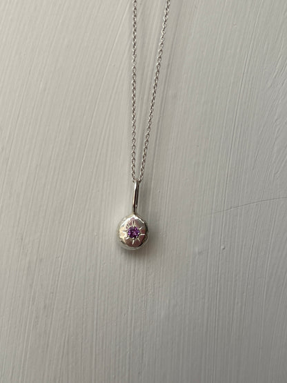 a sterling silver pendant with a star set purple amethyst gemstone on a silver trace chain, pictured against a white background.