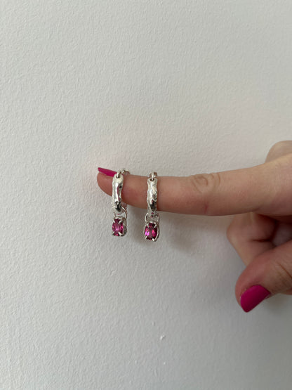 Silver hoops earrings with pink gemstones on a white background