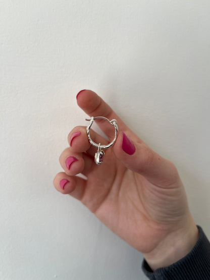 silver earring with pink dangly gemstone against a white background
