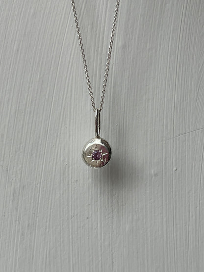 a sterling silver pendant with a star set alexandrite gemstone on a silver trace chain, pictured against a white background.