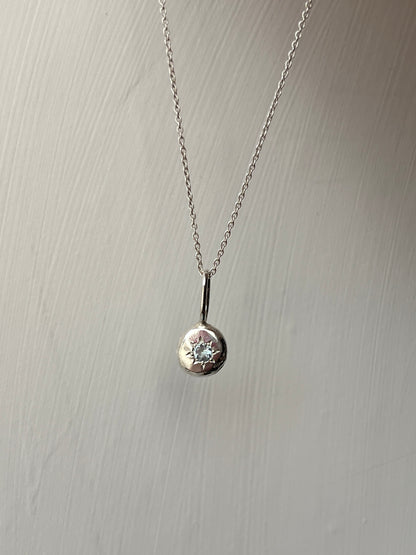 a sterling silver pendant with a star set aqaumarine gemstone on a silver trace chain, pictured against a white background.