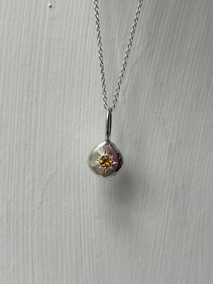 a sterling silver pendant with a star set citrine gemstone on a silver trace chain, pictured against a white background.