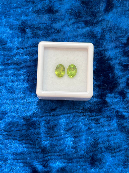 Two green gemstones in a white box on a blue textured background