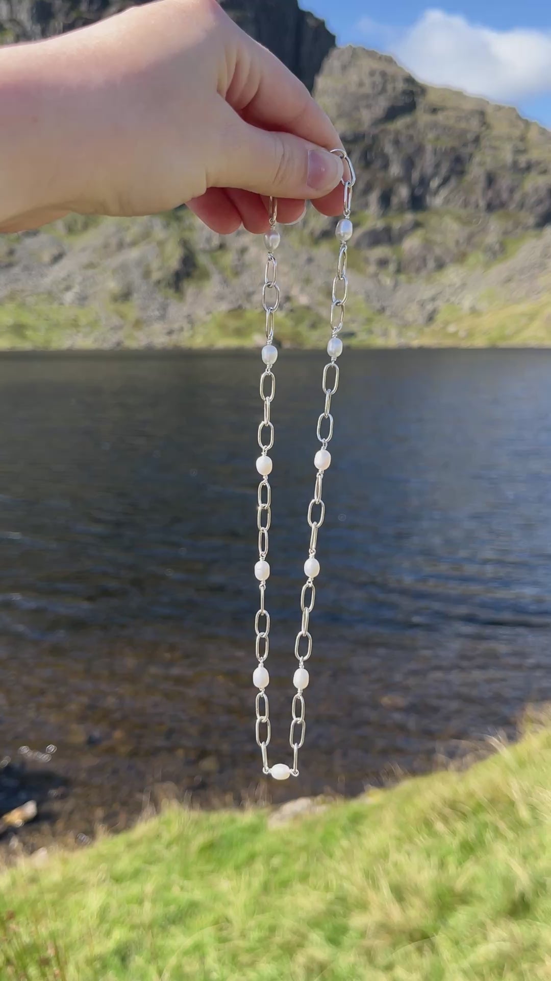 Handmade silver chain necklace with white, freshwater pearls and a t-bar clasp, pictured against a lake