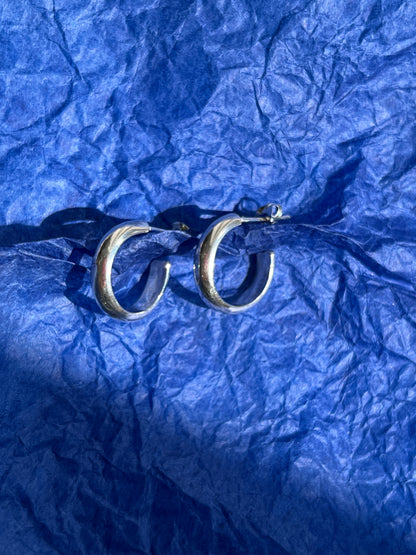 Silver hoop earrings pictured on a blue paper background