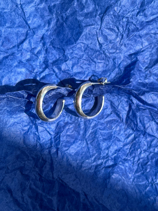 Silver hoop earrings pictured on a blue paper background