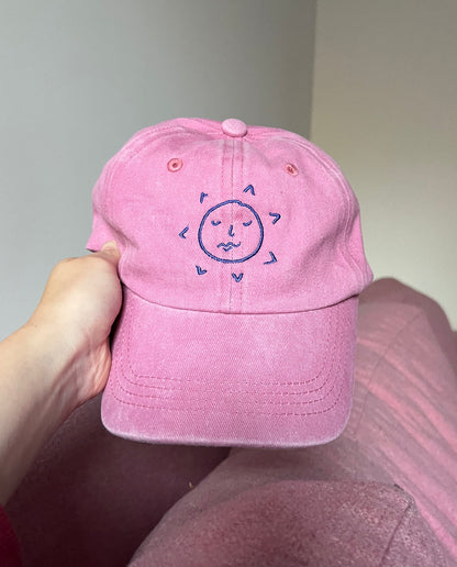 the sunslices pink cap pictured from the front showing the sunface logo