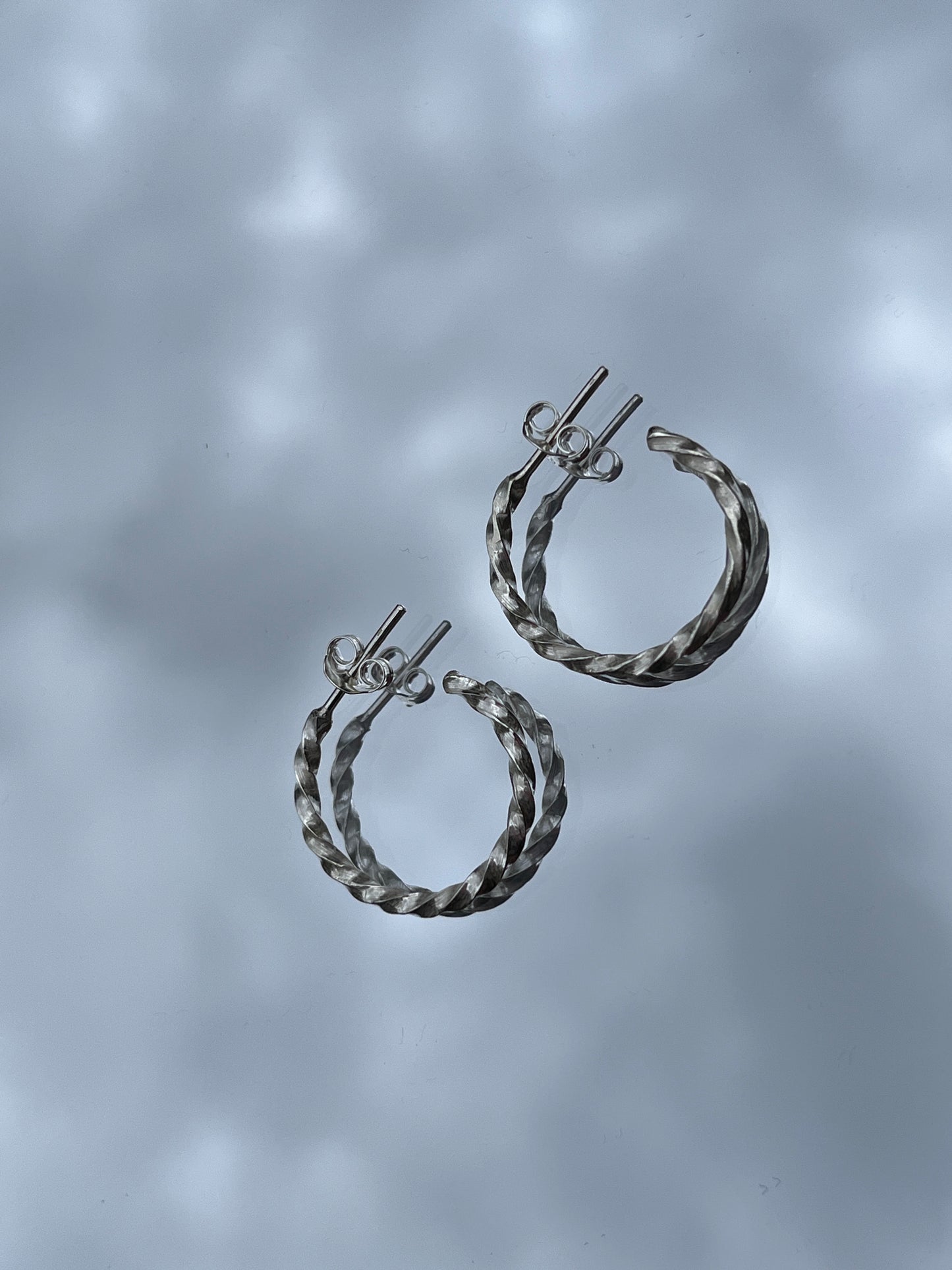 Pair of silver hoop earrings on a gray background