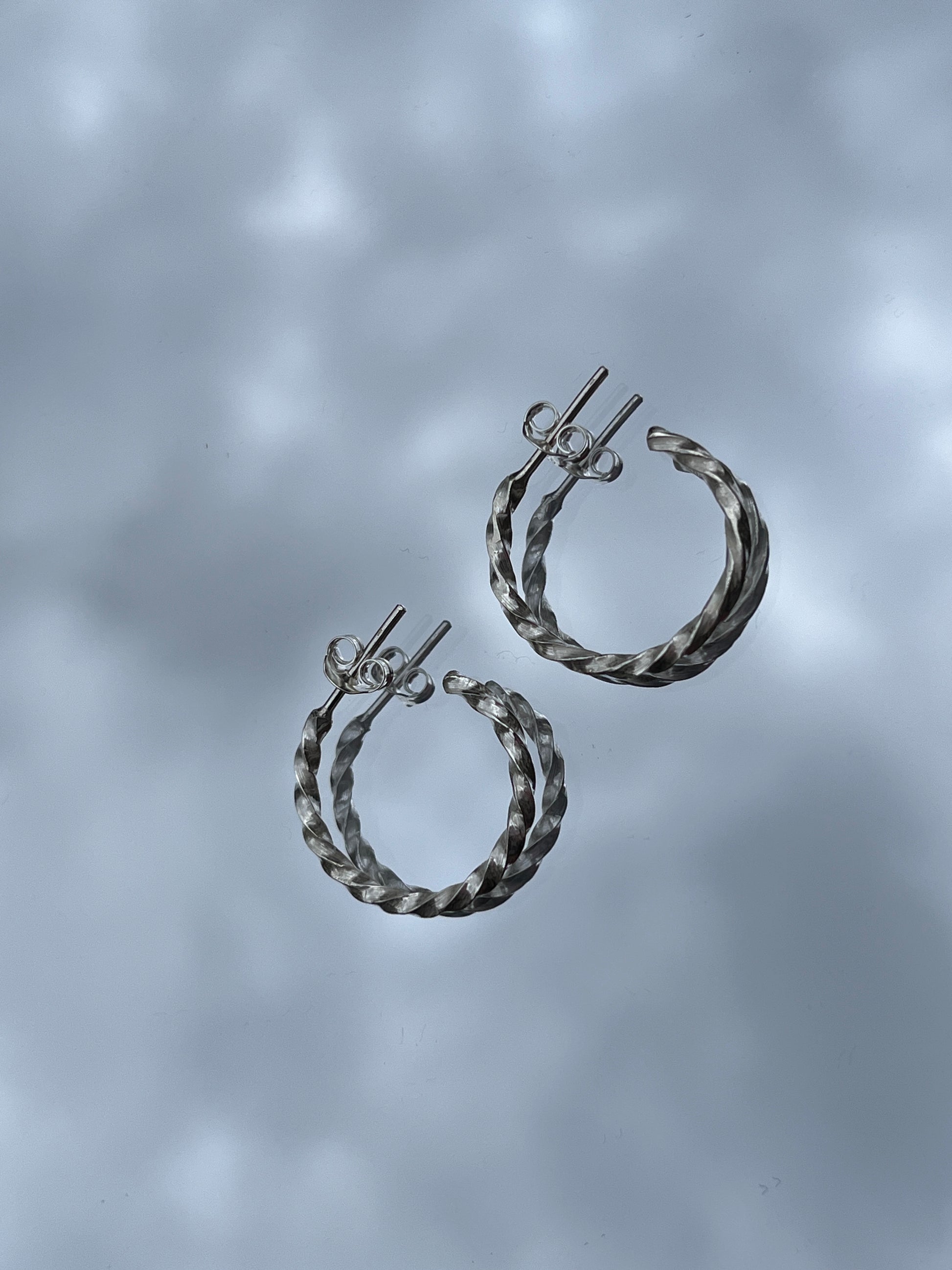 Pair of silver hoop earrings on a gray background