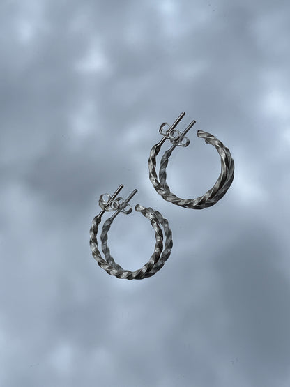 Pair of silver hoop earrings on a gray background