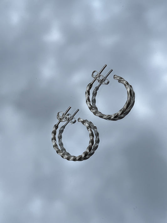 Pair of silver hoop earrings on a gray background
