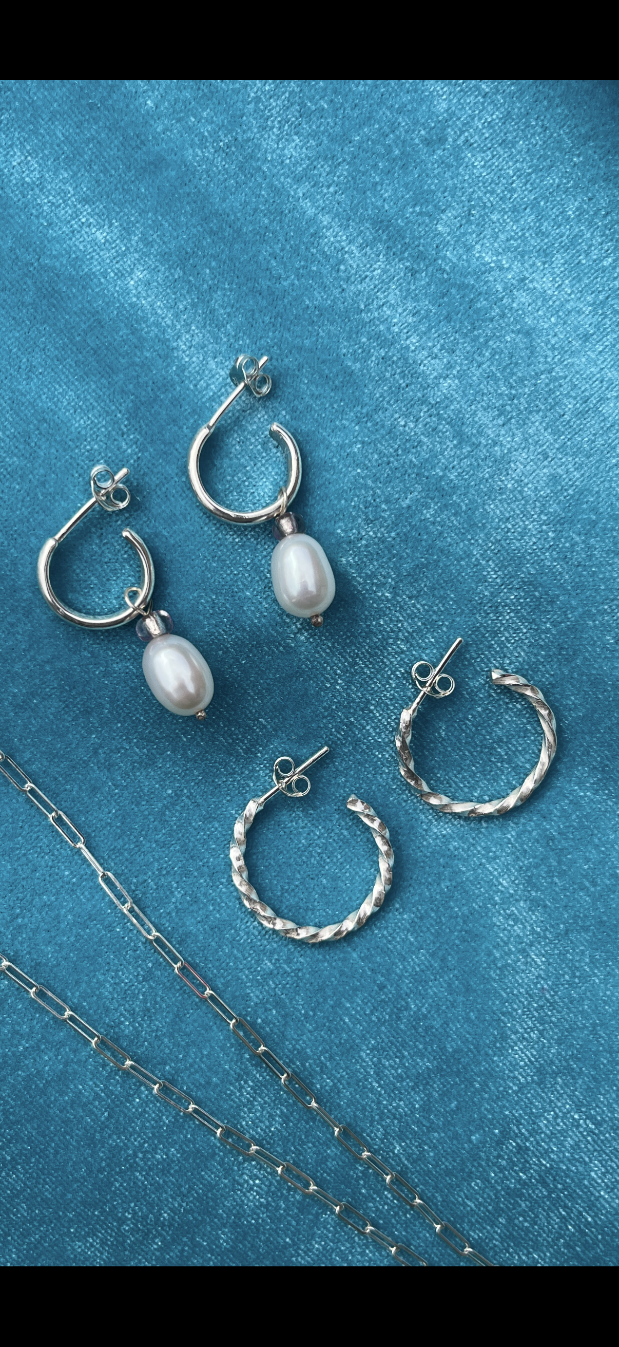 Silver hoop earrings on a blue velvet background