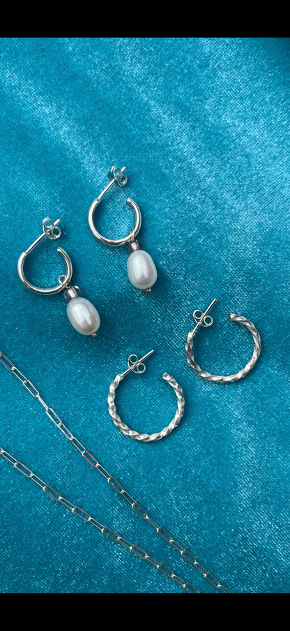 Silver hoop earrings on a blue velvet background